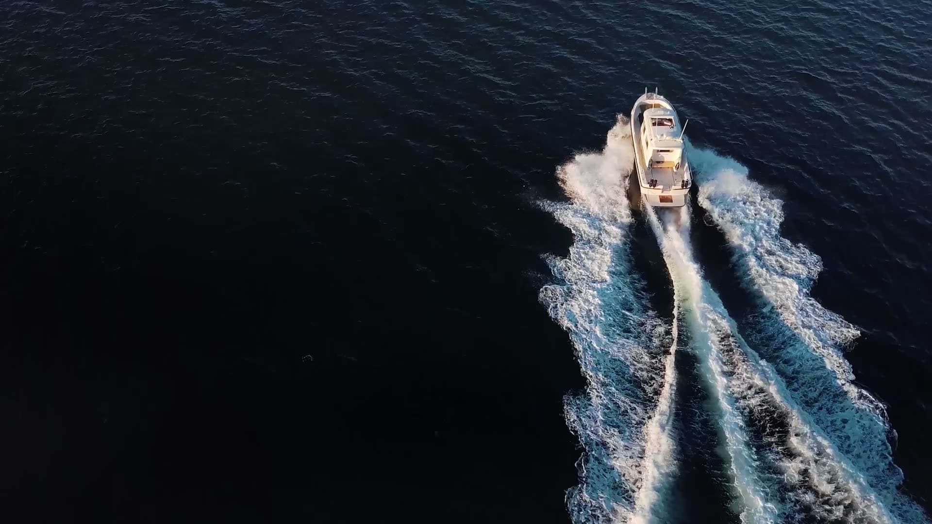 A power yacht under way across open water, seen from above