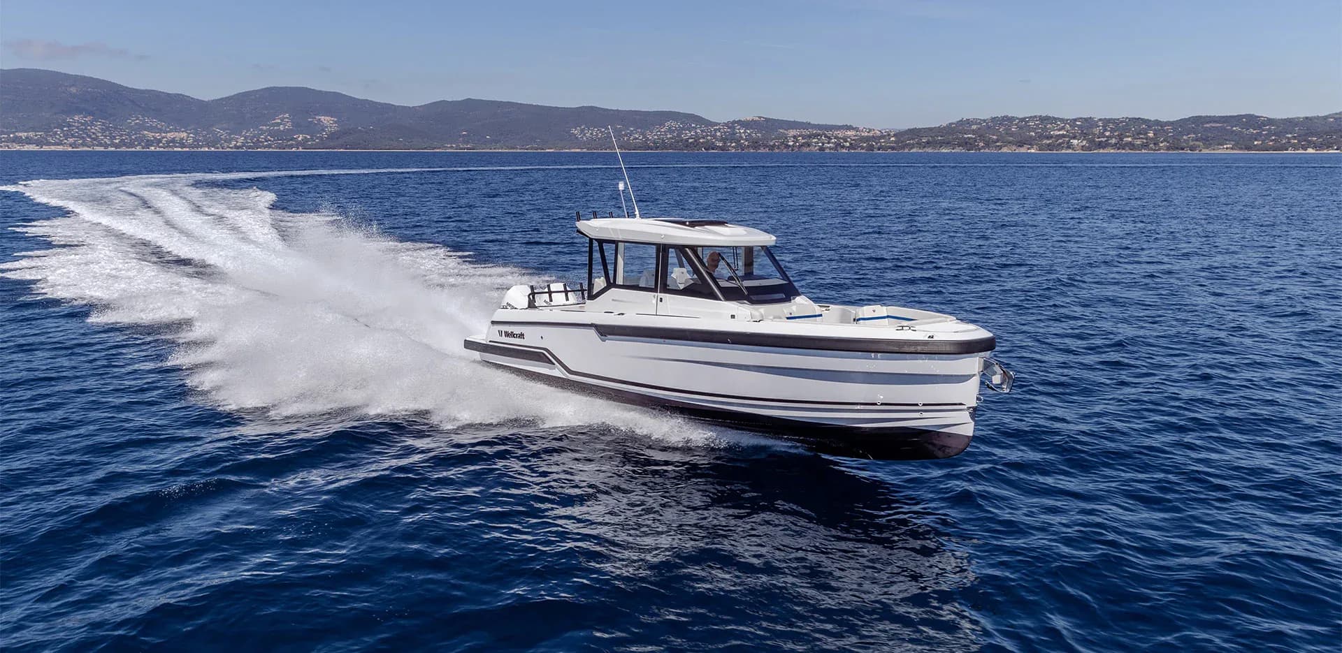 A Wellcraft 28 Explorer running at speed along a rocky coast