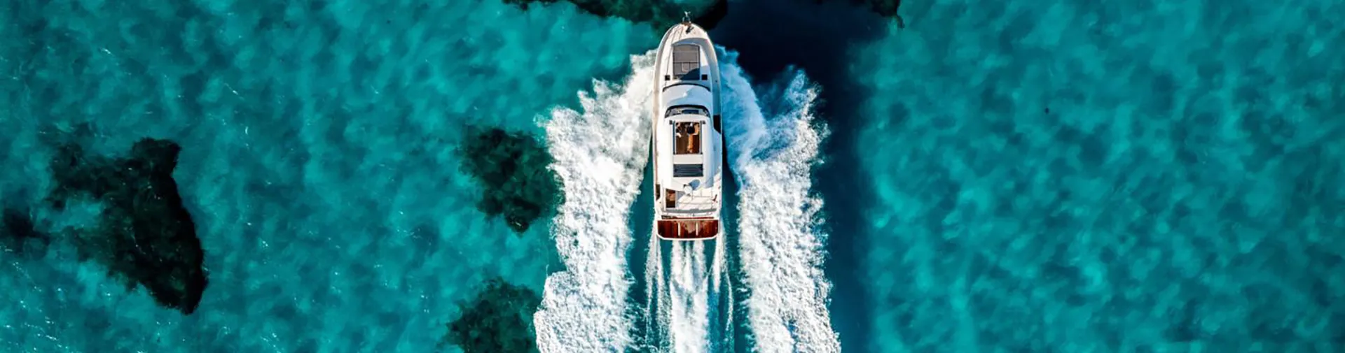 A Beneteau Swift Trawler running across turquoise water, seen from above